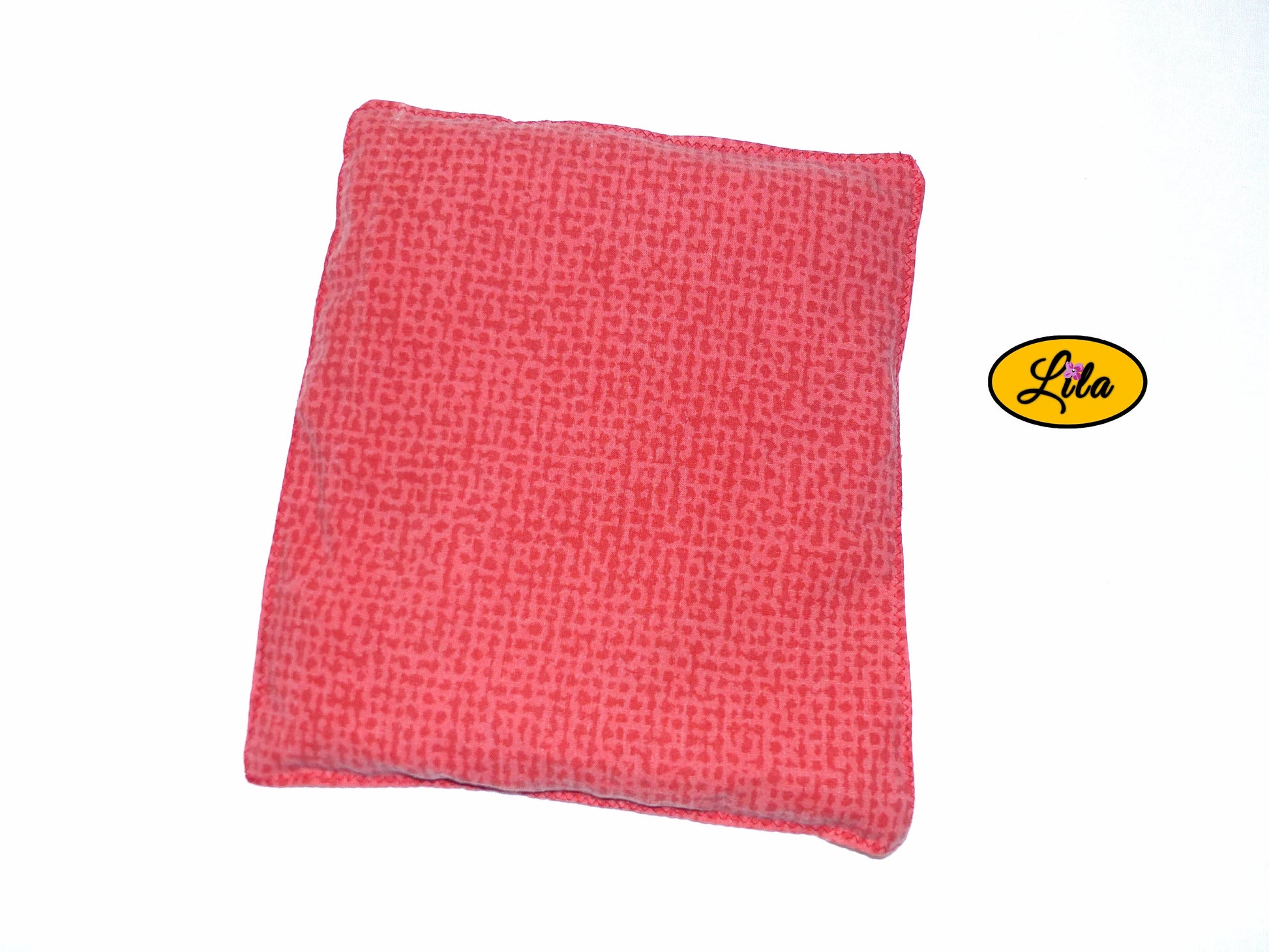 Bouillotte simple rouge et orange réalisée dans d’anciens draps de lit recyclés remplie de noyaux de cerise vue de dos sur fond blanc style artisanal et chaleureux
