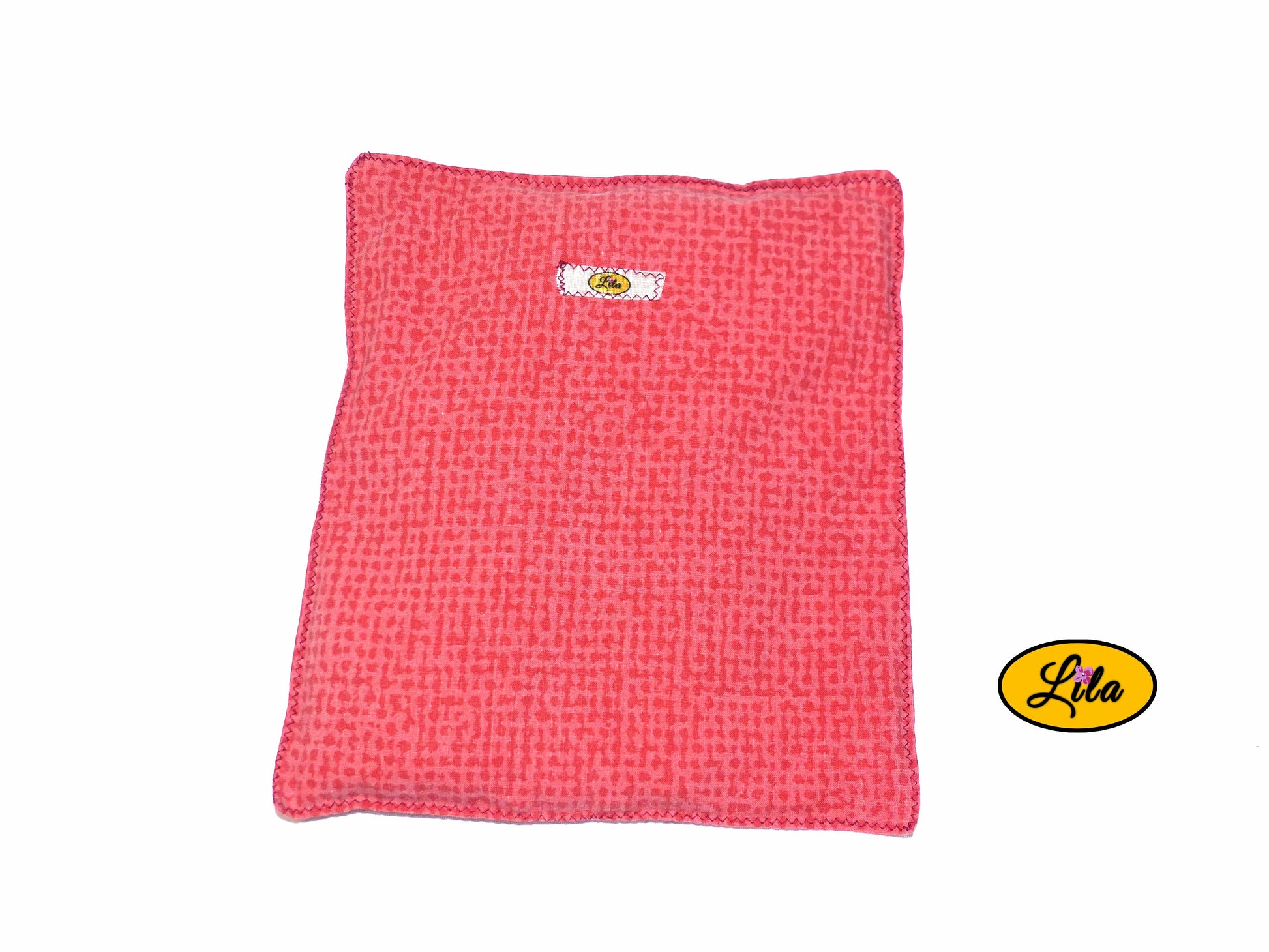 Bouillotte simple rouge et orange réalisée dans d’anciens draps de lit recyclés remplie de noyaux de cerise vue de haut sur fond blanc style naturel et artisanal