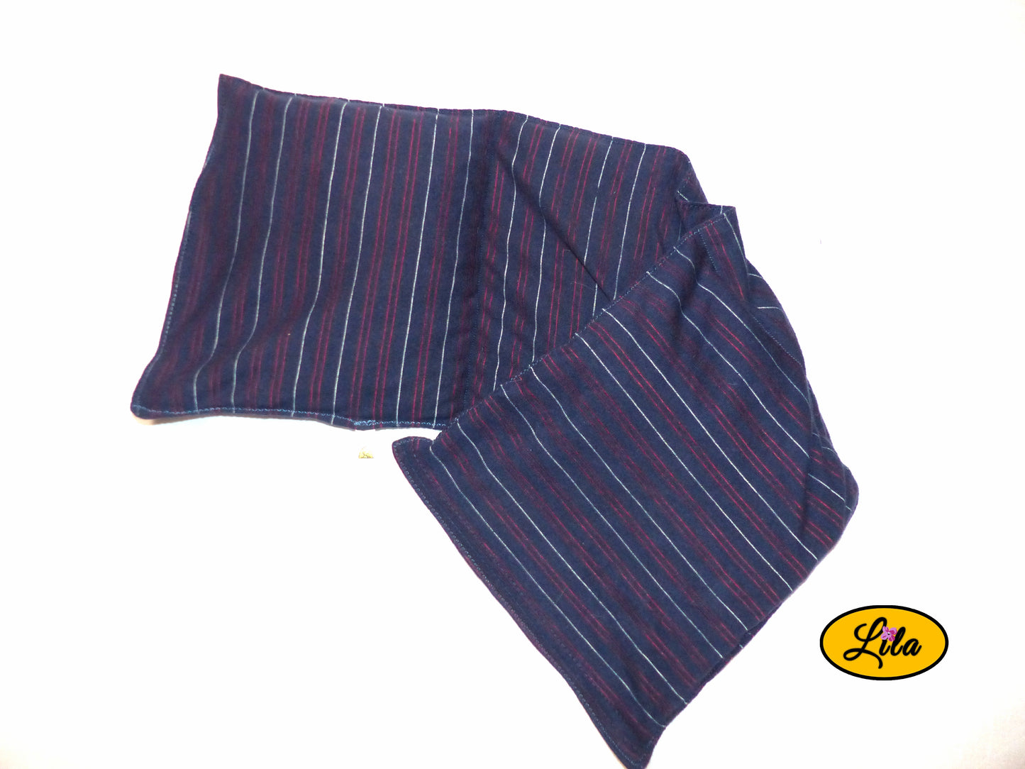 Bouillotte XL bleue à lignes rouges réalisée dans un ancien pyjama recyclé remplie de noyaux de cerise ouverte avec les bords légèrement repliés vue de haut sur fond blanc détail couture et compartiments chauffants