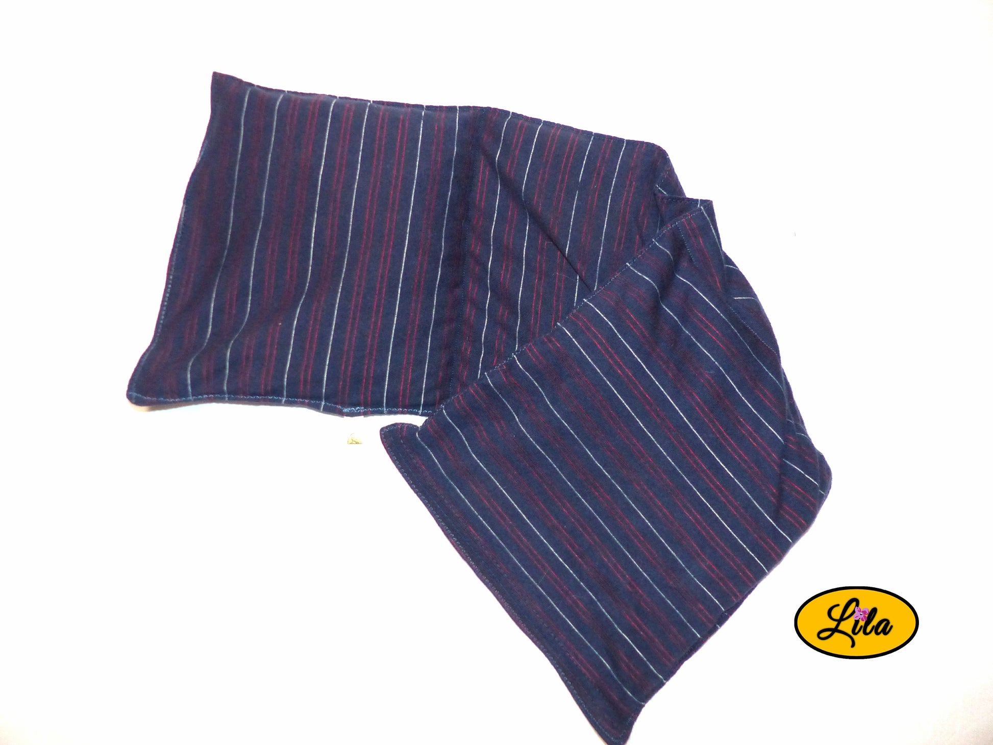Bouillotte XL bleue à lignes rouges réalisée dans un ancien pyjama recyclé remplie de noyaux de cerise ouverte avec les bords légèrement repliés vue de haut sur fond blanc détail couture et compartiments chauffants