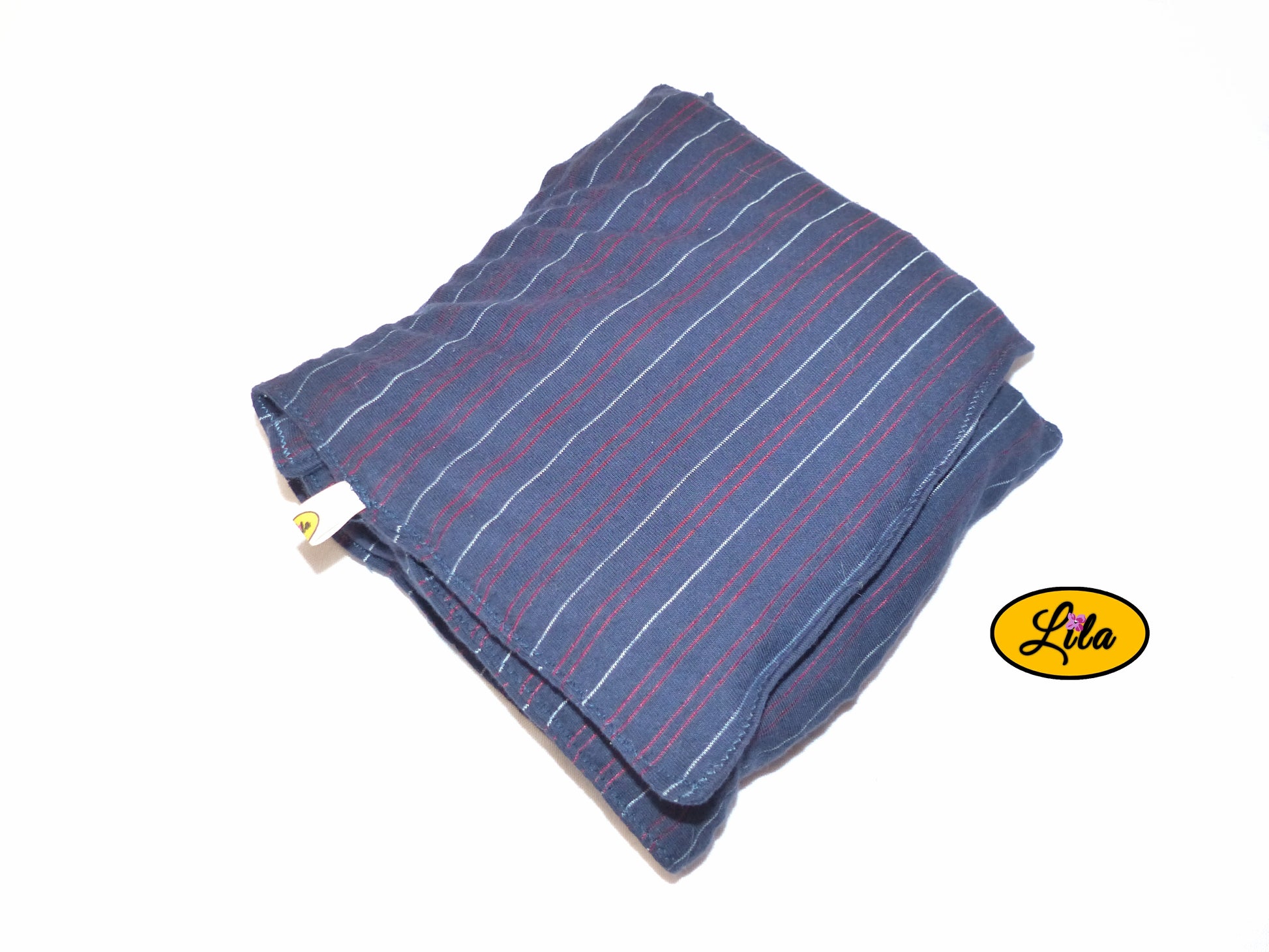 Bouillotte XL bleue à lignes rouges réalisée dans un ancien pyjama recyclé remplie de noyaux de cerise pliée en trois vue de haut sur fond blanc style cocooning et naturel