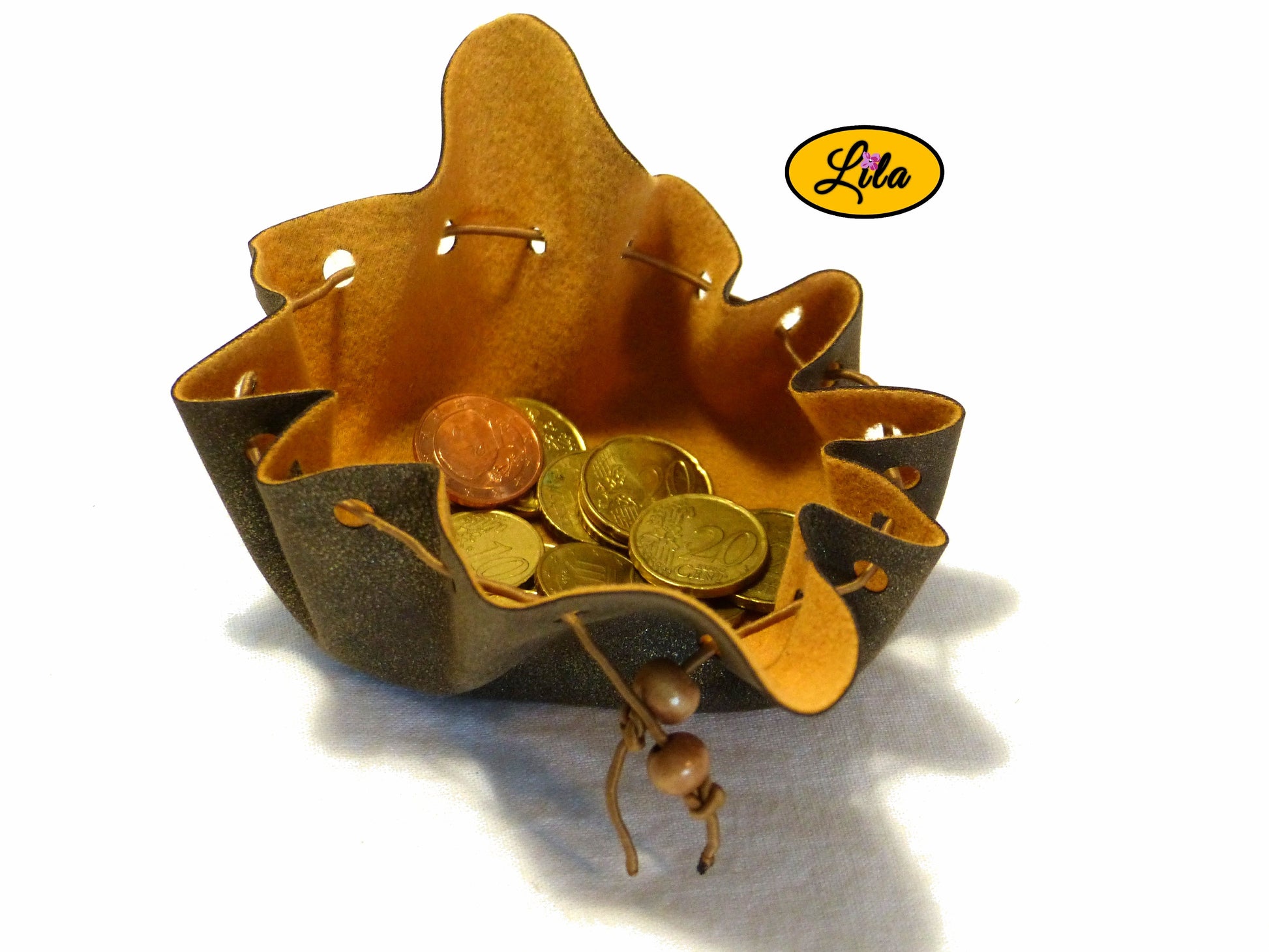 Bourse brune effet doré en simili cuir ouverte vue de haut avec pièces de monnaie visibles à l’intérieur sur fond blanc style pratique et artisanal