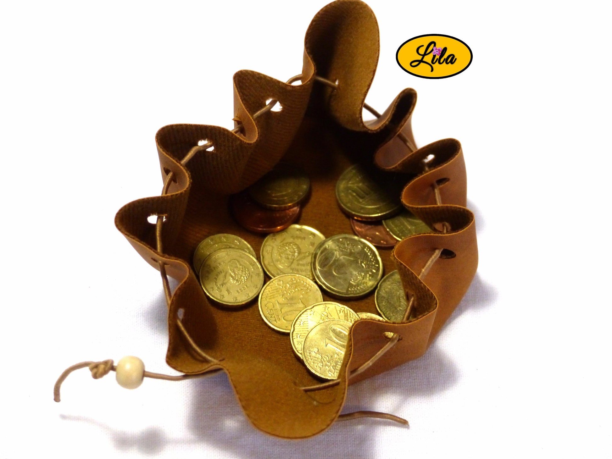 Vue rapprochée d’une bourse brune en simili cuir avec perles en bois et cordons de fermeture sur fond blanc style bohème et vintage