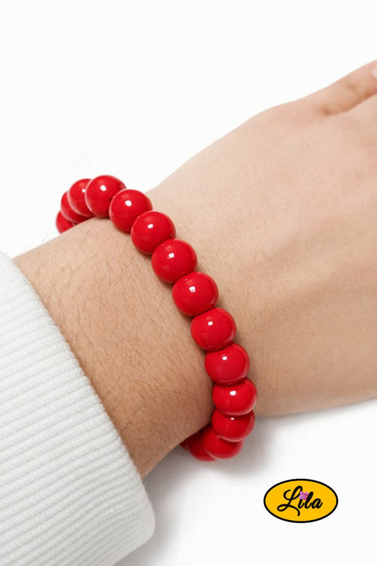 Bracelet en fausses perles rouges porté au poignet style élégant