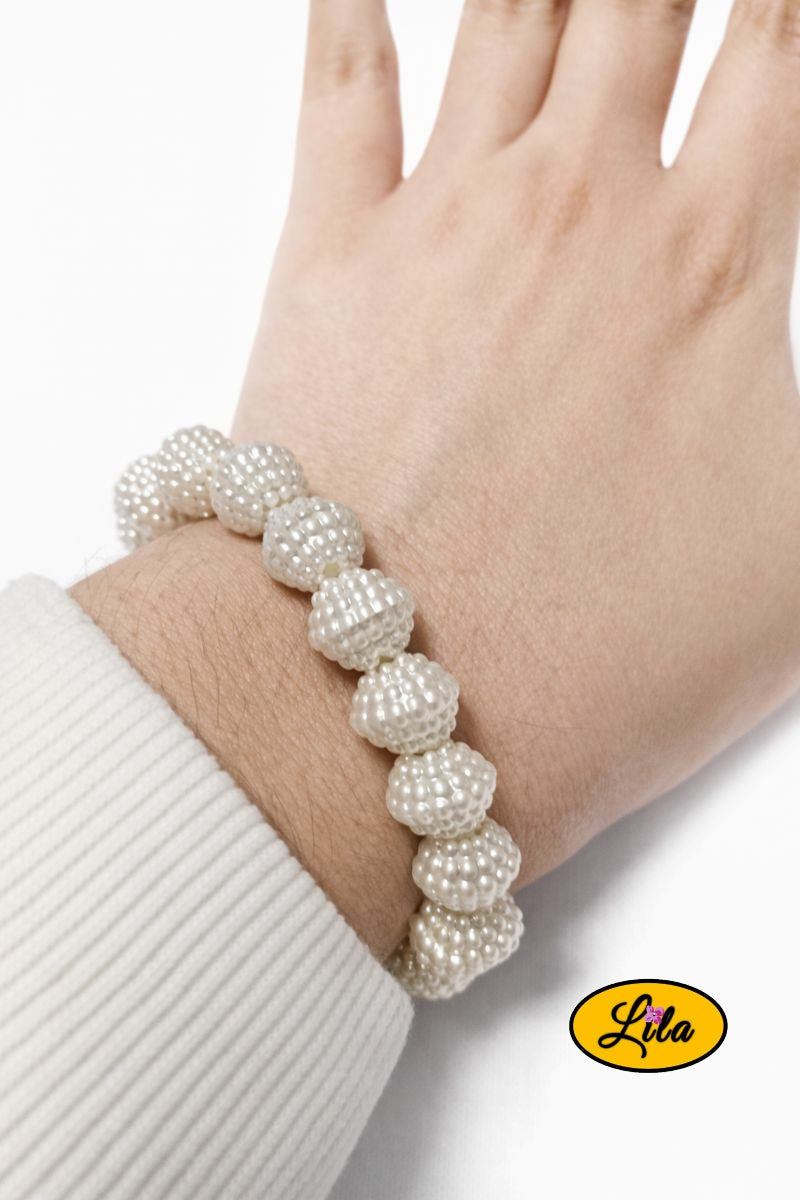 Bracelet en perles blanches structurées porté au poignet style élégant