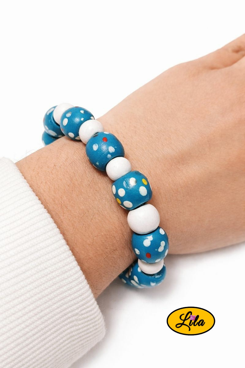 Bracelet en perles de bois bleues à pois blancs alternées avec petites perles blanches porté au poignet style rétro
