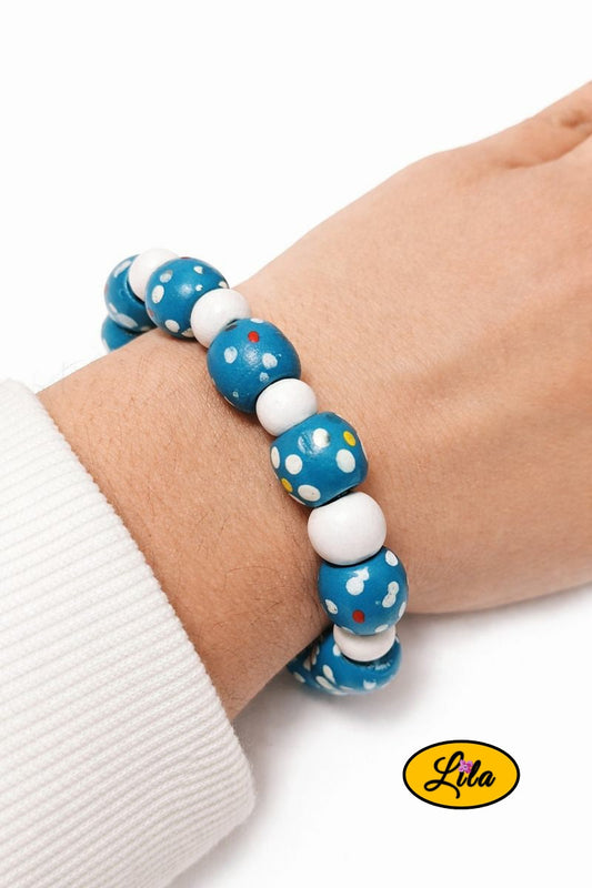 Bracelet en perles de bois bleues à pois blancs alternées avec petites perles blanches porté au poignet style rétro