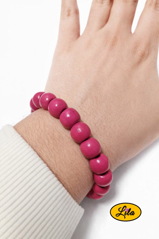 Bracelet en perles rondes en bois rose foncé porté au poignet style naturel