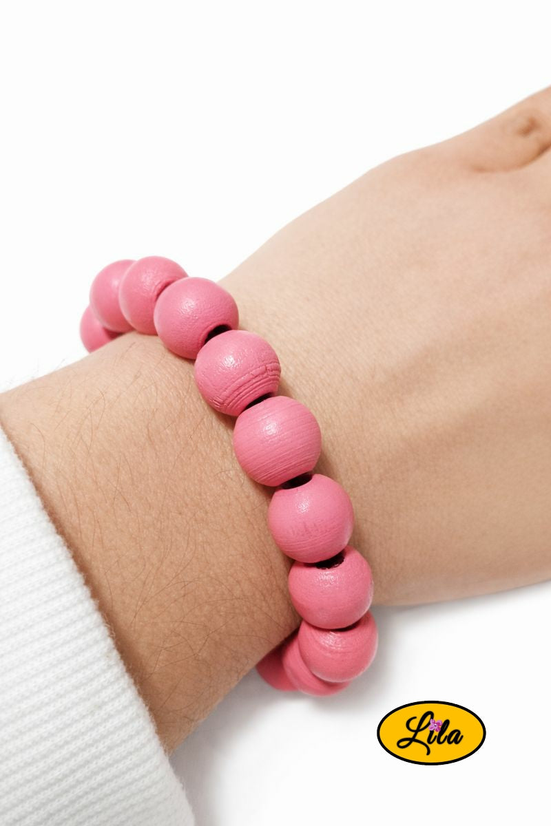 Bracelet en perles rondes en bois rose porté au poignet style naturel