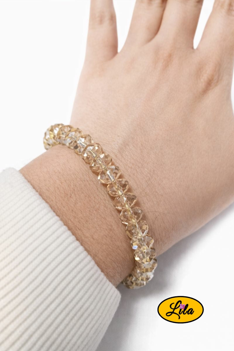 Bracelet en perles jaunes transparentes forme géométrique porté au poignet style lumineux