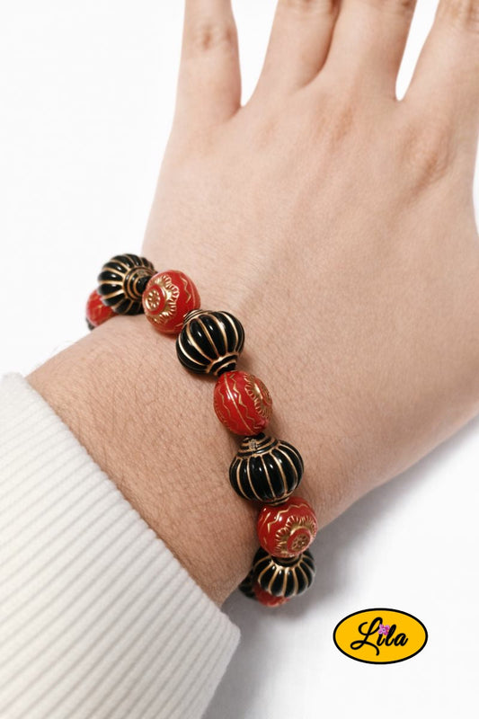 Bracelet avec perles en forme de lanternes rouges et noires porté au poignet style original