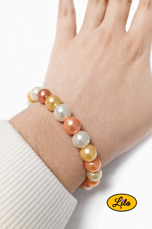 Bracelet en fausses perles nacrées blanches jaunes et orange porté au poignet style lumineux