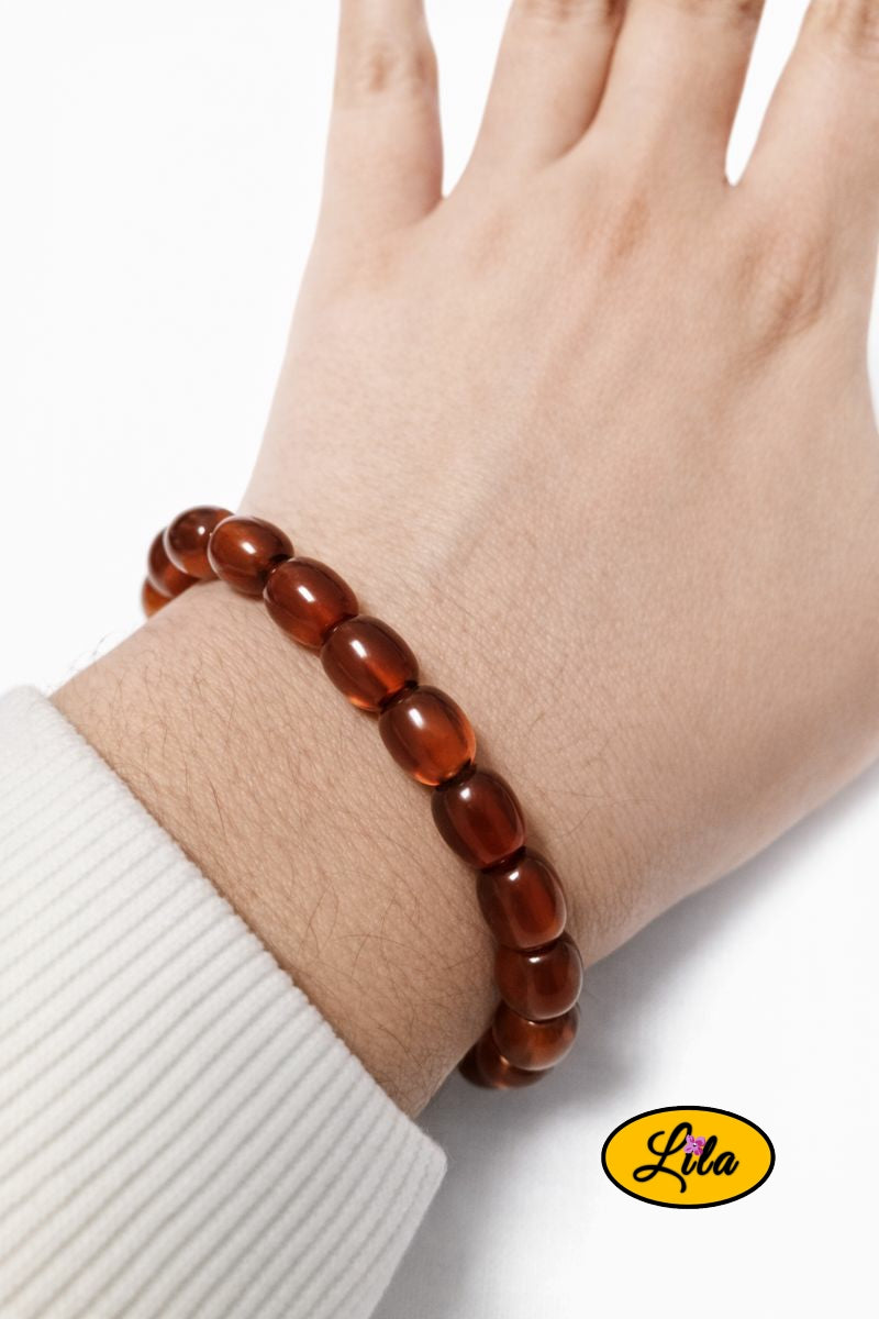 Bracelet en fausses perles ovales ambrées porté au poignet style chaleureux