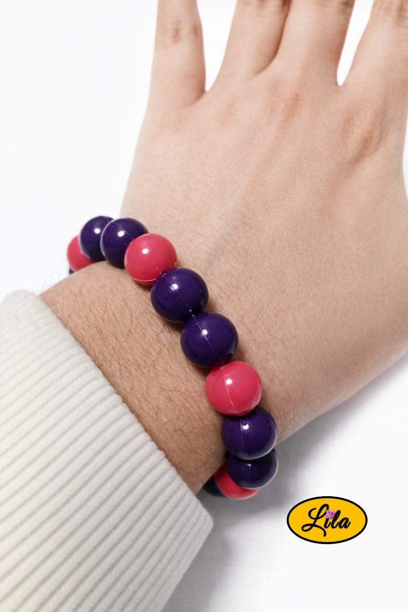 Bracelet de perles rondes mauves et roses porté au poignet style délicat