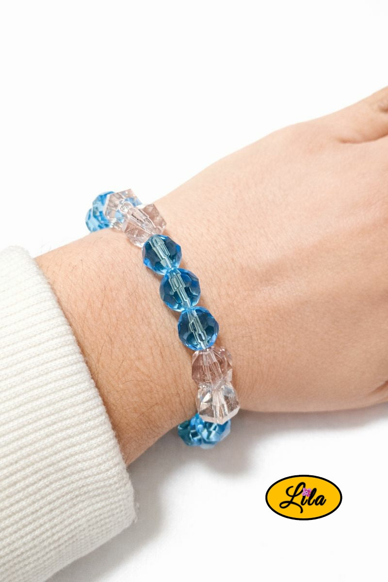 Bracelet en fausses perles transparentes et bleu ciel porté au poignet style léger et lumineux