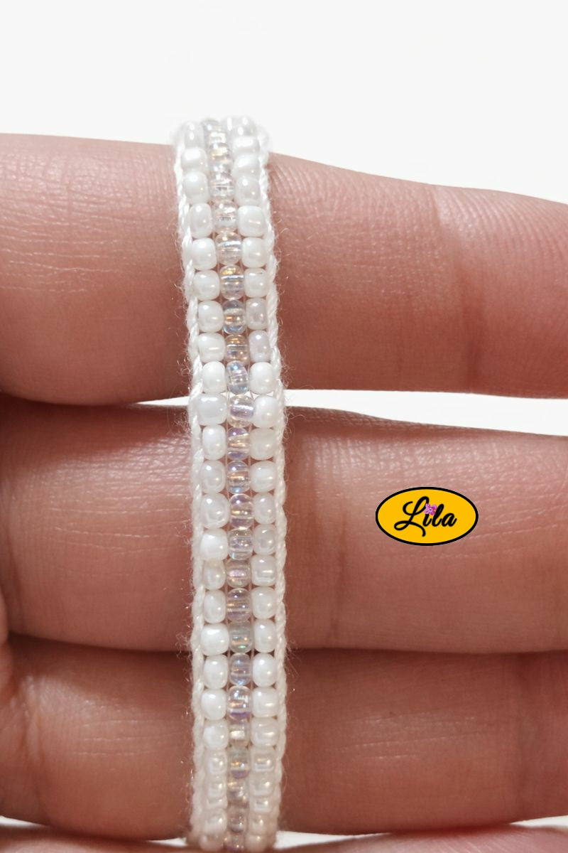 Détail tissage bracelet en perles de rocailles blanches tenu en main
