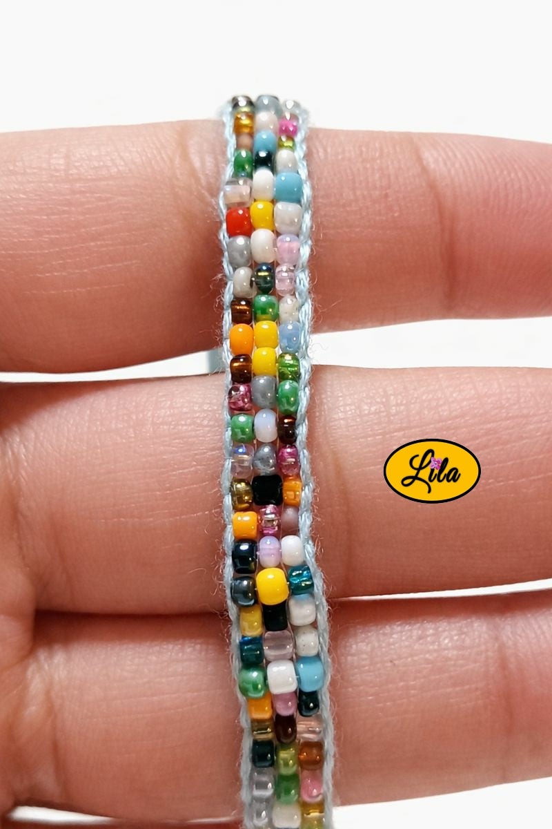 Détail tissage bracelet multicolore en perles de rocailles tenu en main