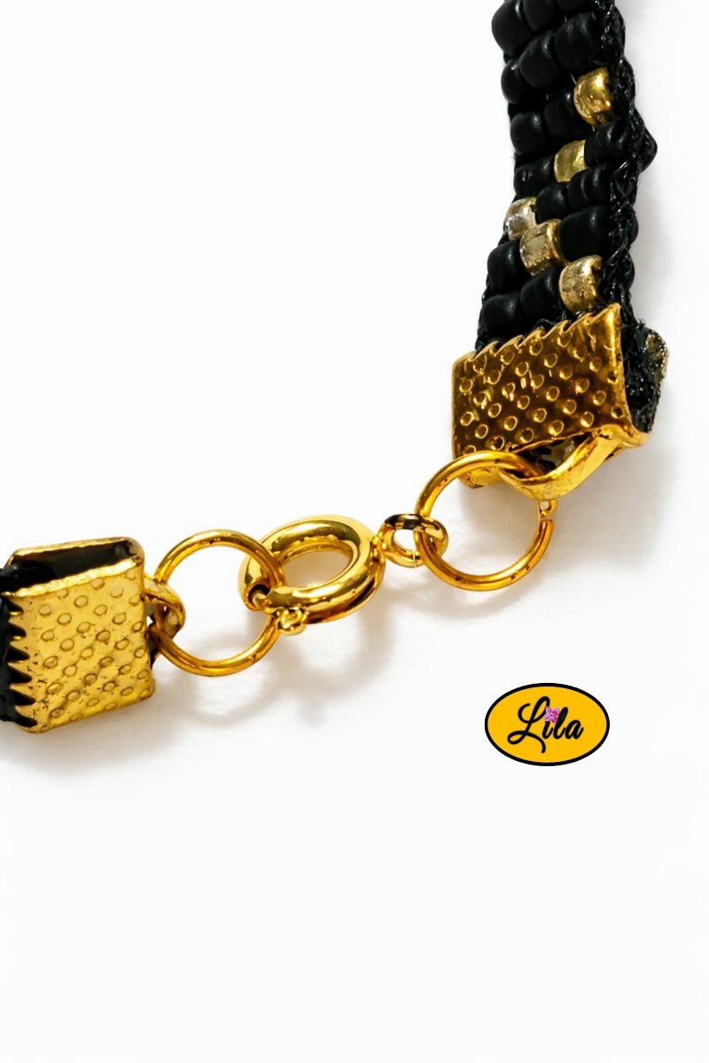 Détail attache dorée bracelet tissé en perles de rocailles noires et dorées