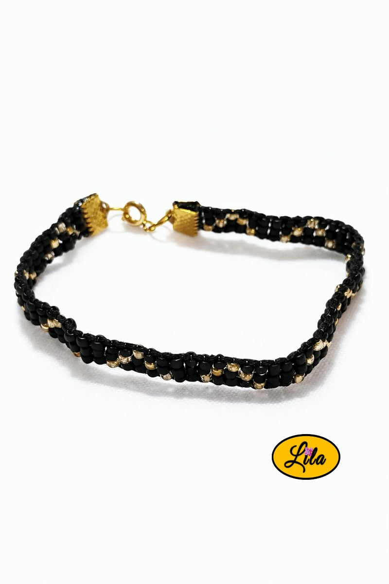 Bracelet tissé perles de rocailles noires et dorées sur fond blanc vue produit