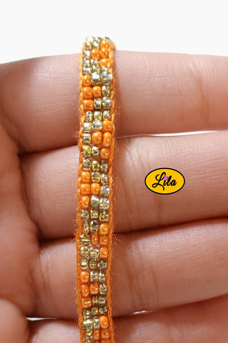 Détail tissage bracelet en perles de rocailles orange et doré tenu en main