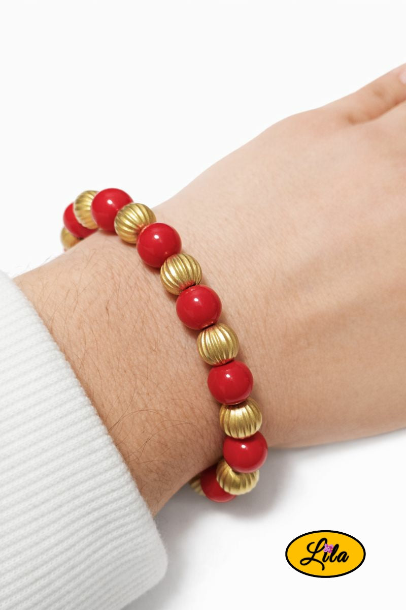 Bracelet rouge et doré porté au poignet style élégant