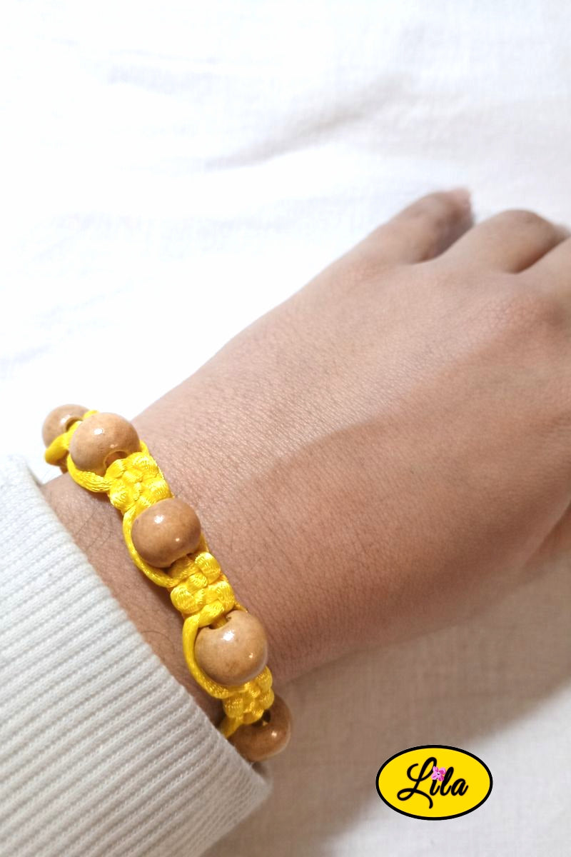 Bracelet Shamballa fil jaune avec perles de bois porté au poignet style naturel lumineux