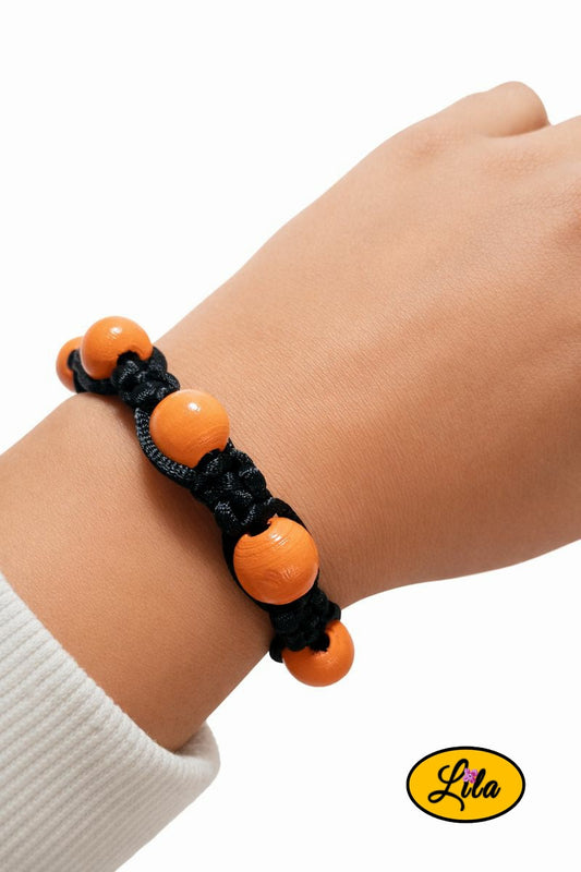 Bracelet Shamballa fil noir avec perles de bois orange porté au poignet style contrasté