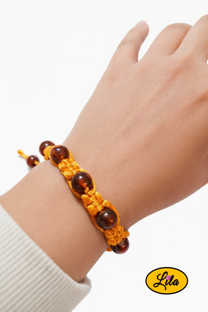 Bracelet Shamballa fil orange avec perles ambrées porté au poignet style lumineux