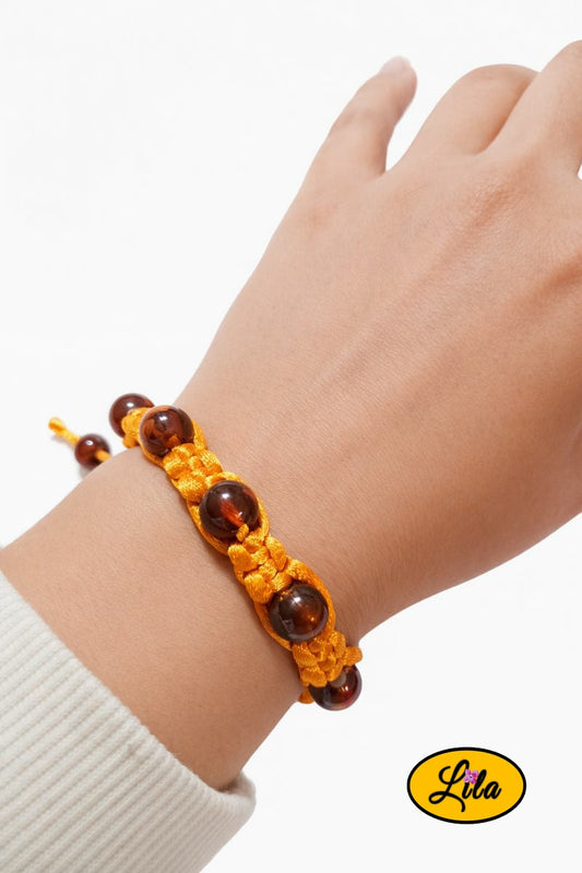 Bracelet Shamballa fil orange avec perles ambrées porté au poignet style lumineux