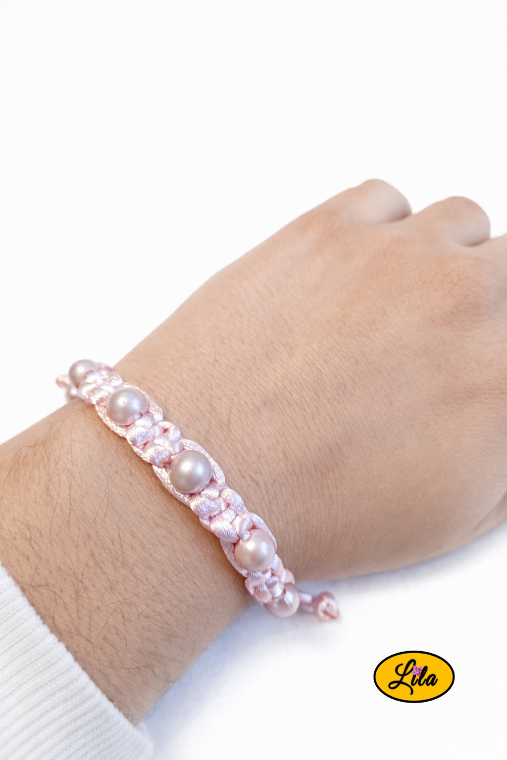 Bracelet Shamballa fil rose clair avec perles roses nacrées porté au poignet style élégant