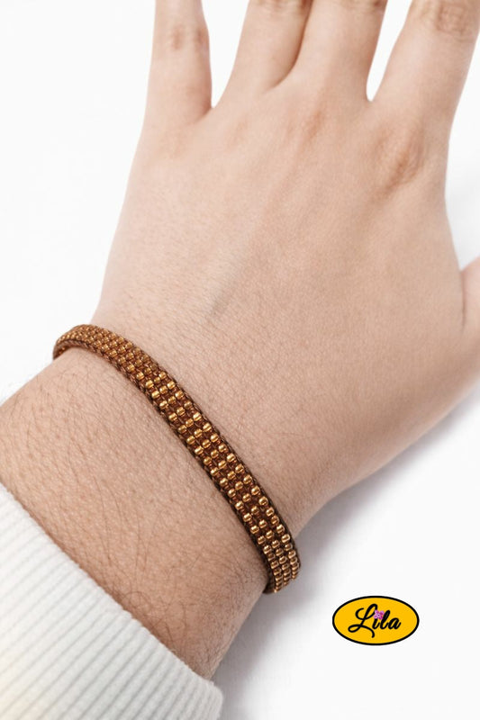 Bracelet tissé en perles de rocailles dorées porté au poignet style élégant