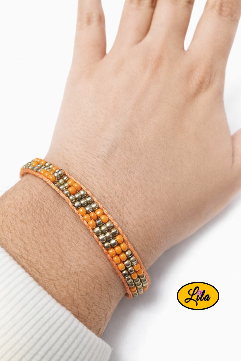 Bracelet tissé en perles de rocailles orange et doré porté au poignet style artisanal
