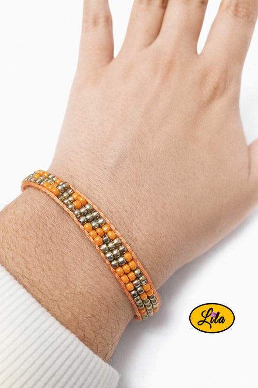 Bracelet tissé en perles de rocailles orange et doré porté au poignet style artisanal