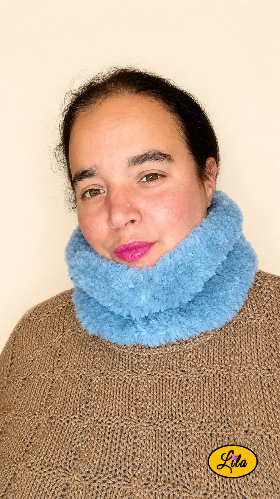 Cache-cou tricoté main bleu effet fausse fourrure porté dans le cou par une femme avec pull brun sur fond crème vue de face style chaud et tendance