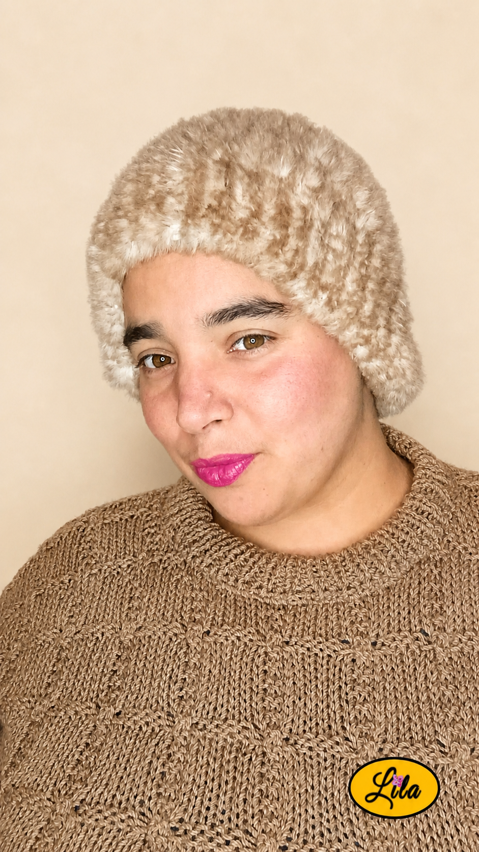 Cache-cou tricoté main brun chamarré effet fausse fourrure porté sur la tête par une femme avec pull brun sur fond crème tête légèrement de profil droit style cocooning et élégant