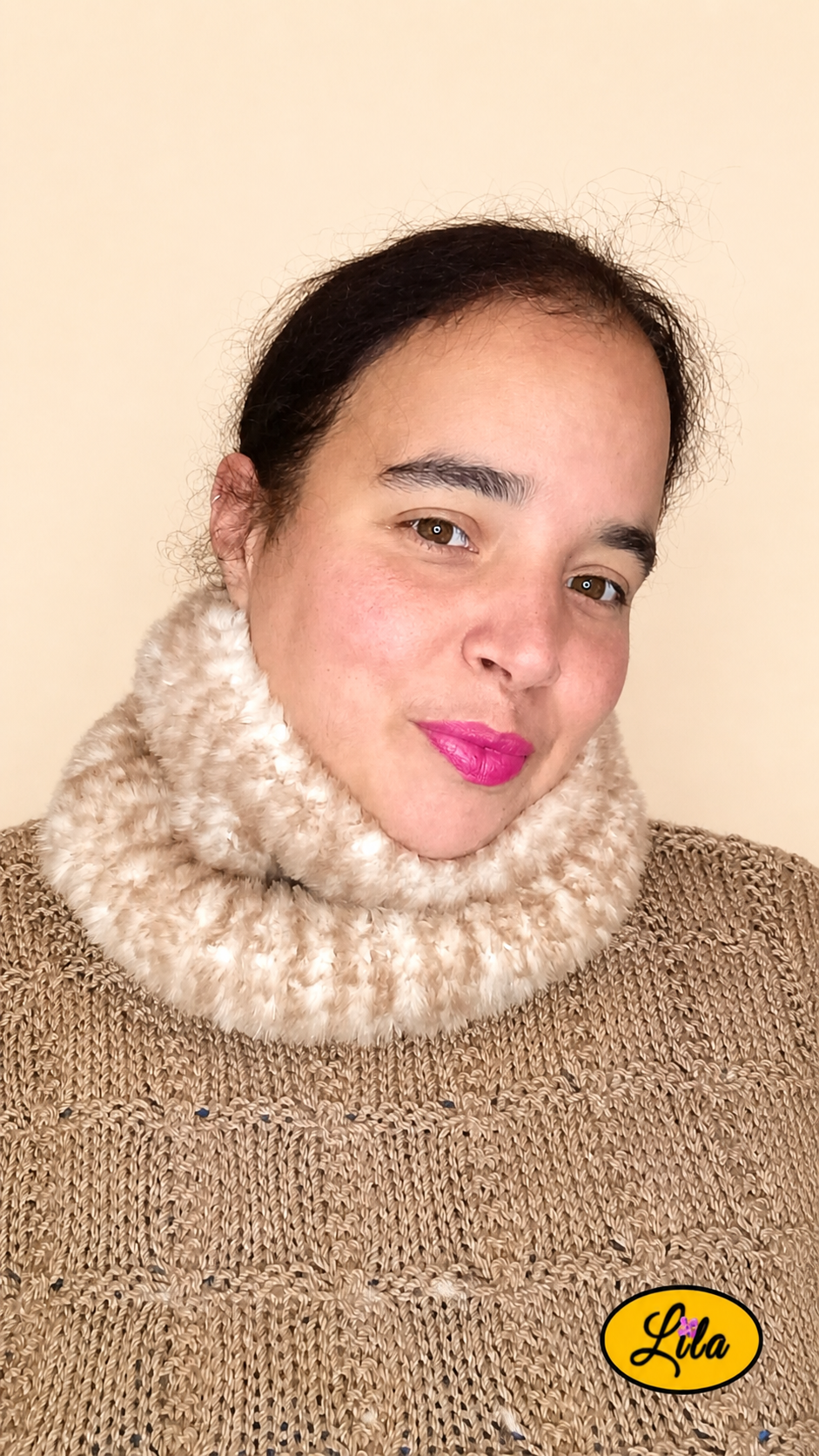 Cache-cou tricoté main brun chamarré effet fausse fourrure porté dans le cou par une femme avec pull brun sur fond crème tête tournée vers le profil gauche style chaleureux et tendance