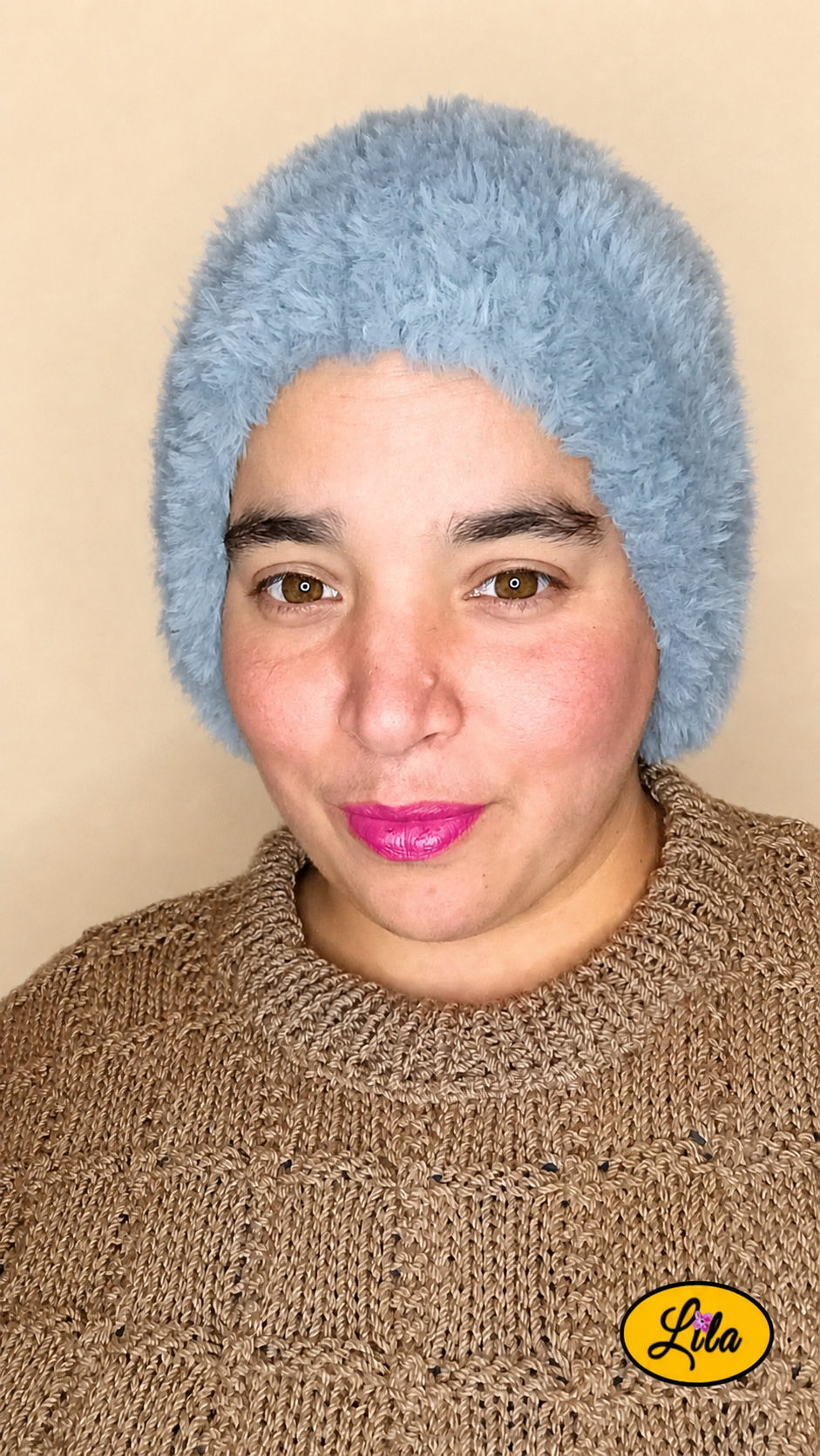 Cache-cou tricoté main gris effet fausse fourrure porté sur la tête par une femme avec pull brun sur fond crème vue de face style doux et hivernal