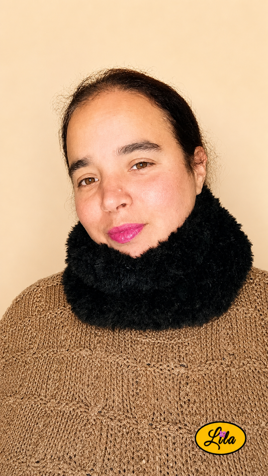 Cache-cou tricoté main noir effet fausse fourrure porté dans le cou par une femme avec pull brun sur fond crème tête légèrement tournée vers la droite style doux et tendance