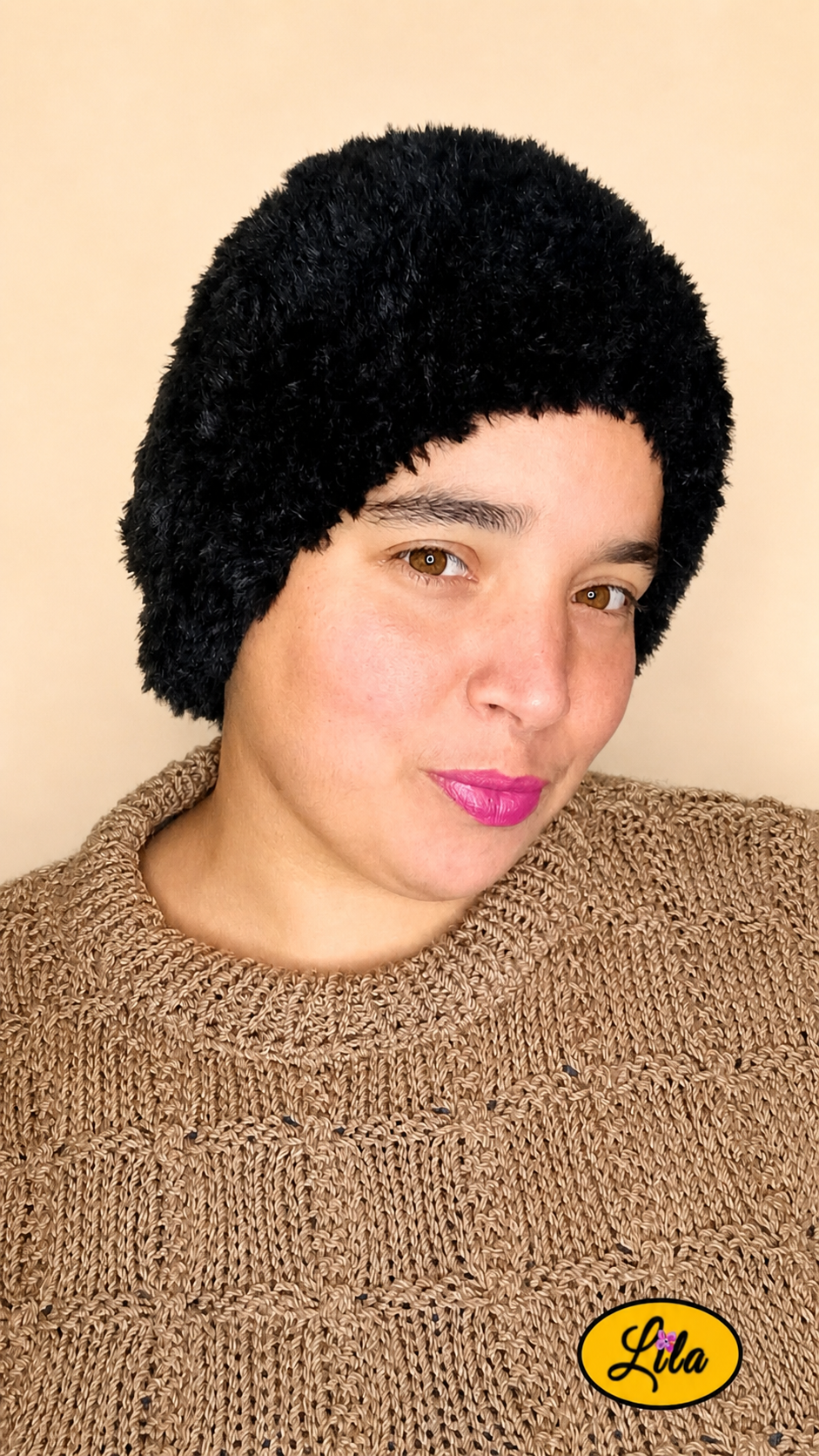 Cache-cou tricoté main noir effet fausse fourrure porté sur la tête par une femme avec pull brun sur fond crème tête légèrement tournée vers la gauche style chic et cocooning