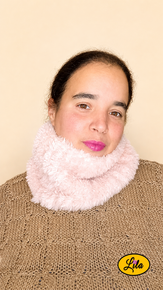Cache-cou tricoté main rose clair effet fausse fourrure porté dans le cou par une femme avec pull brun sur fond crème tête légèrement tournée vers la gauche style chaleureux et élégant