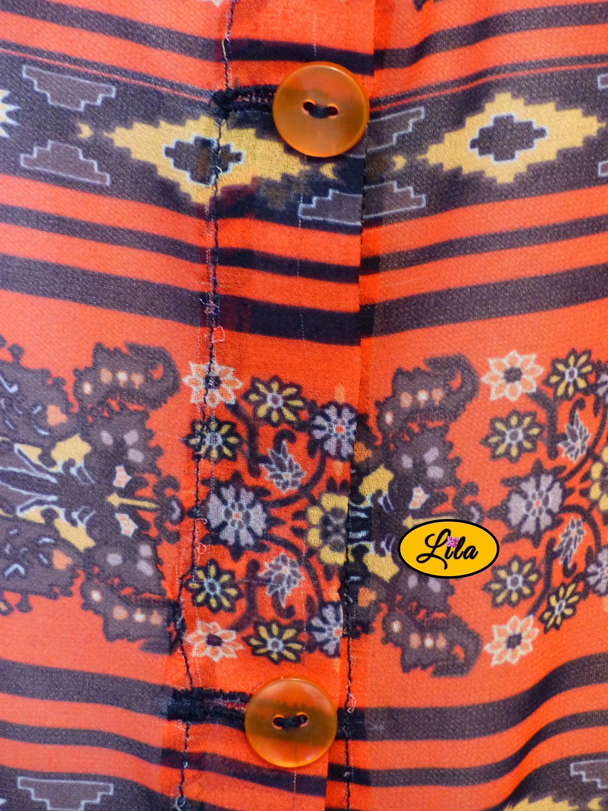 Zoom sur les boutons assortis du chemisier Delphine sans manches en tissu orange et noir détail couture et finition élégante
