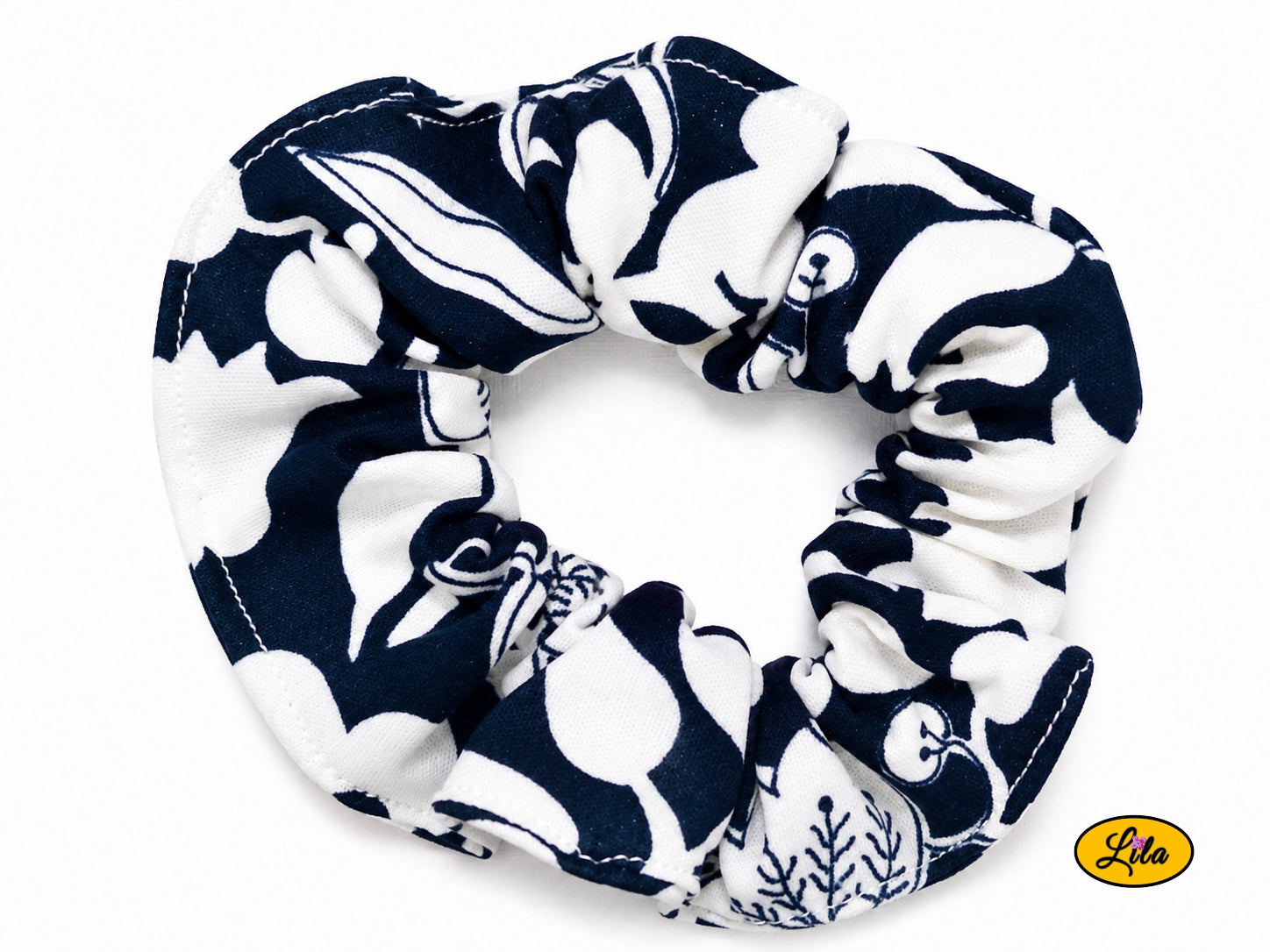 Chouchou pour cheveux en tissu bleu marine à motifs floraux blancs présenté sur fond blanc style élégant et artisanal