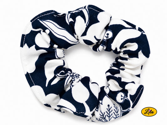 Chouchou pour cheveux en tissu bleu marine à motifs floraux blancs présenté sur fond blanc style élégant et artisanal
