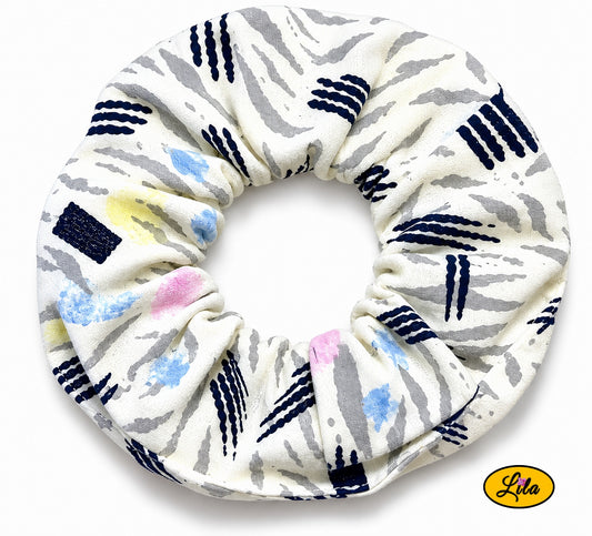 Chouchou pour cheveux en tissu aux couleurs mixtes présenté sur fond blanc style coloré et artisanal