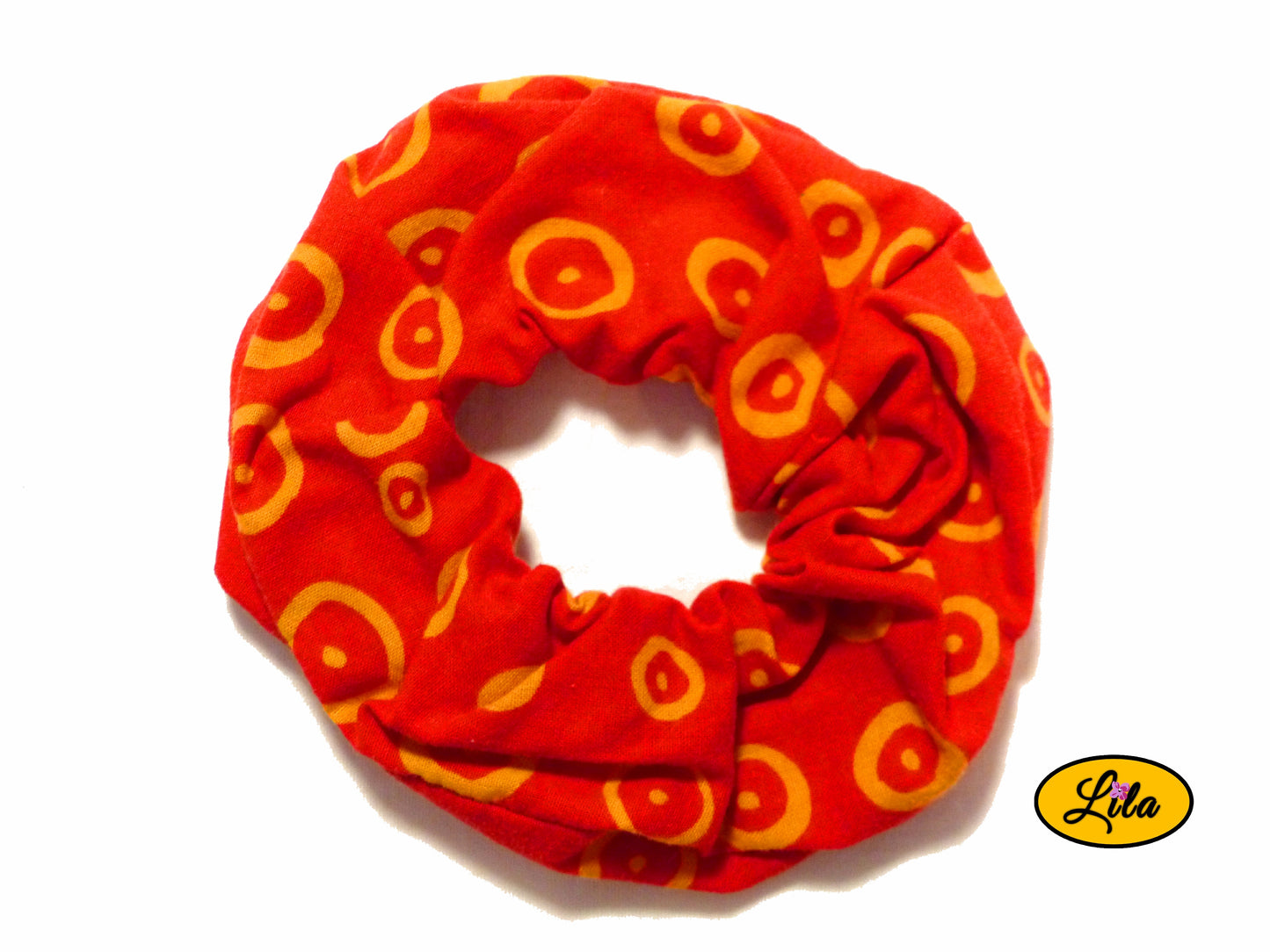 Chouchou pour cheveux en tissu rouge avec motifs de ronds orange présenté sur fond blanc style rétro et artisanal
