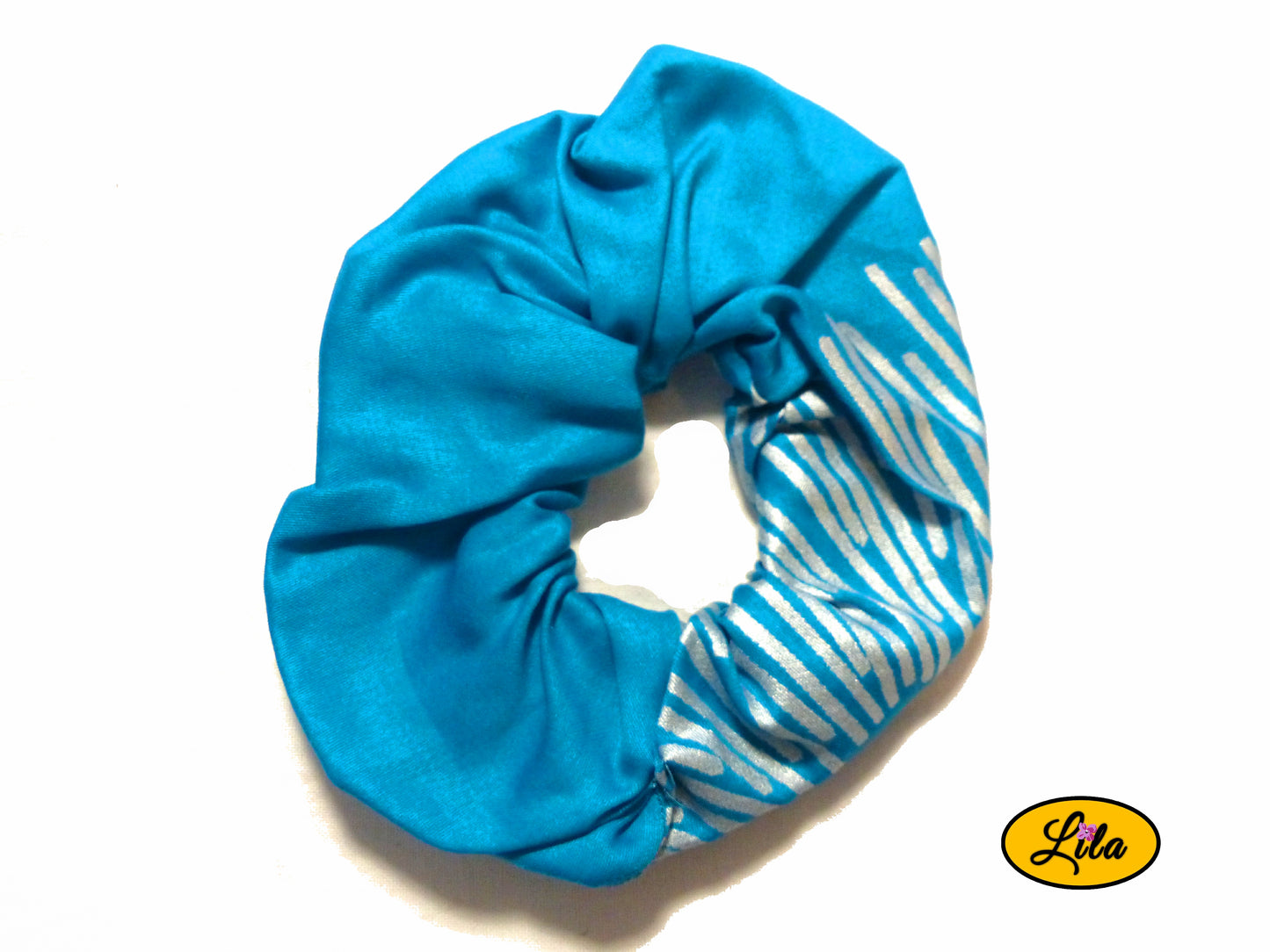 Chouchou pour cheveux en tissu turquoise avec quelques lignes argentées visibles sur le bas droit présenté sur fond blanc style moderne et artisanal