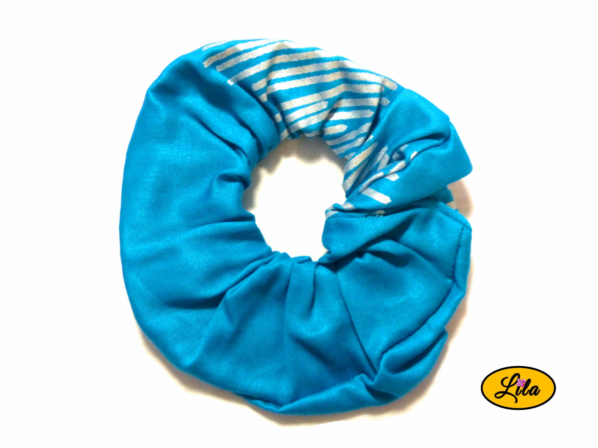 Chouchou pour cheveux en tissu turquoise avec motifs de lignes argentées visibles sur la partie supérieure présenté sur fond blanc style élégant et artisanal