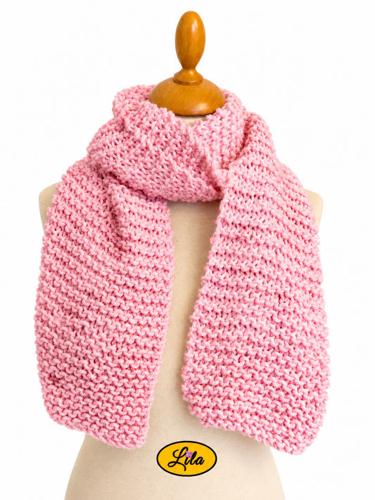 Écharpe rose tricotée à la main enroulée autour d’un mannequin de couture avec les côtés pendants sur fond blanc style chic et cocooning