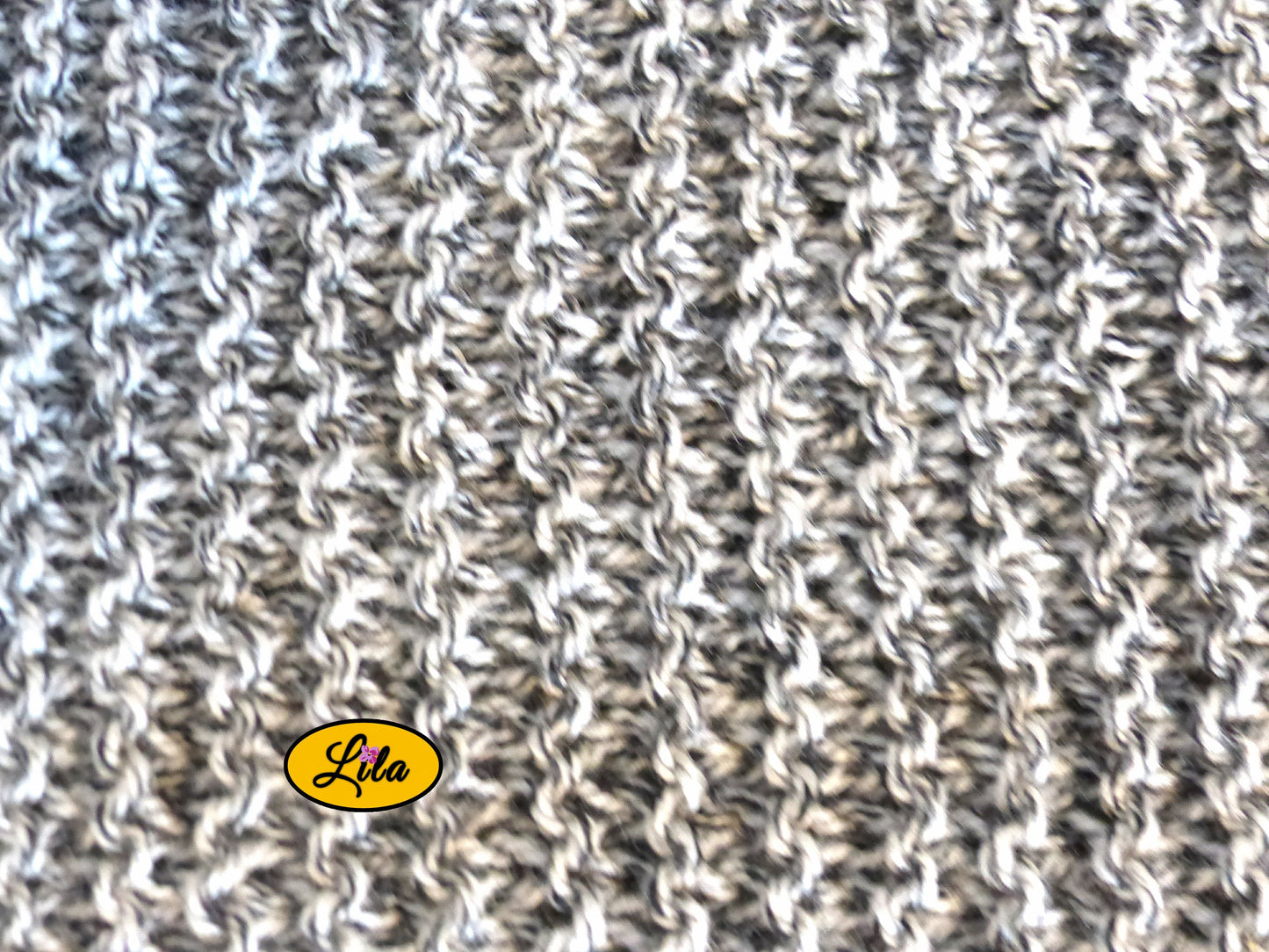 Zoom sur une écharpe tricotée main grise chamarrée avec vue détaillée sur le point de tricot la texture et les nuances de gris style cocooning et artisanal