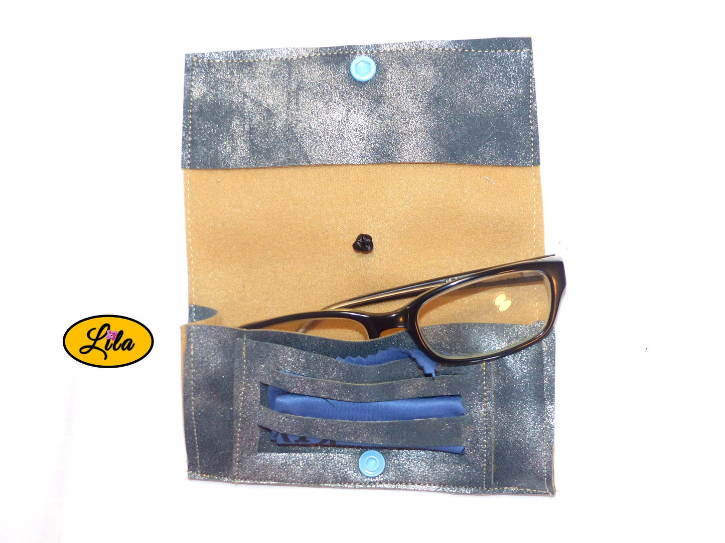 Étui à lunettes en simili bleu argenté ouvert à plat avec paire de lunettes et lingettes rangées dans le compartiment intérieur sur fond blanc style artisanal et moderne
